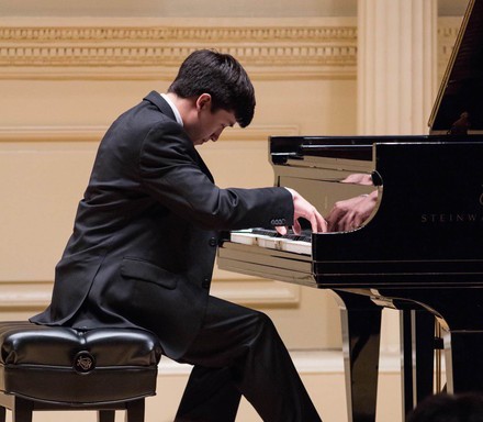 Yong Murray at a piano. He is dressed in a suit and passionately playing.