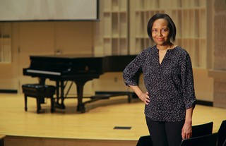Professor Kimberly Mack stands with a hand on one hip in a concert hall.