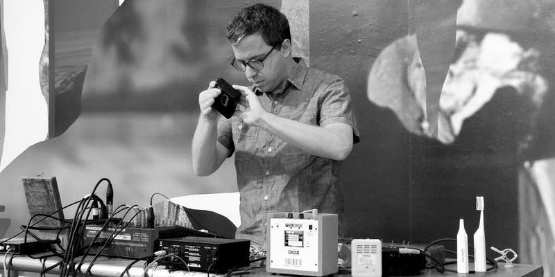 Seth Cluett in black and white, holding electronics equipment.