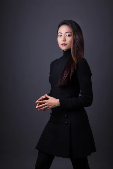 Audrey Vardanega. She is dressed all in black on a charcoal gray background.