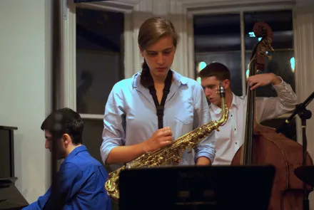 Kira Daglio-Fine with two other musicians. She is holding a saxophone.