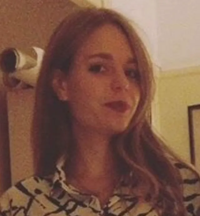 Audrey Amsellem stands in a white and black shirt with long hair.