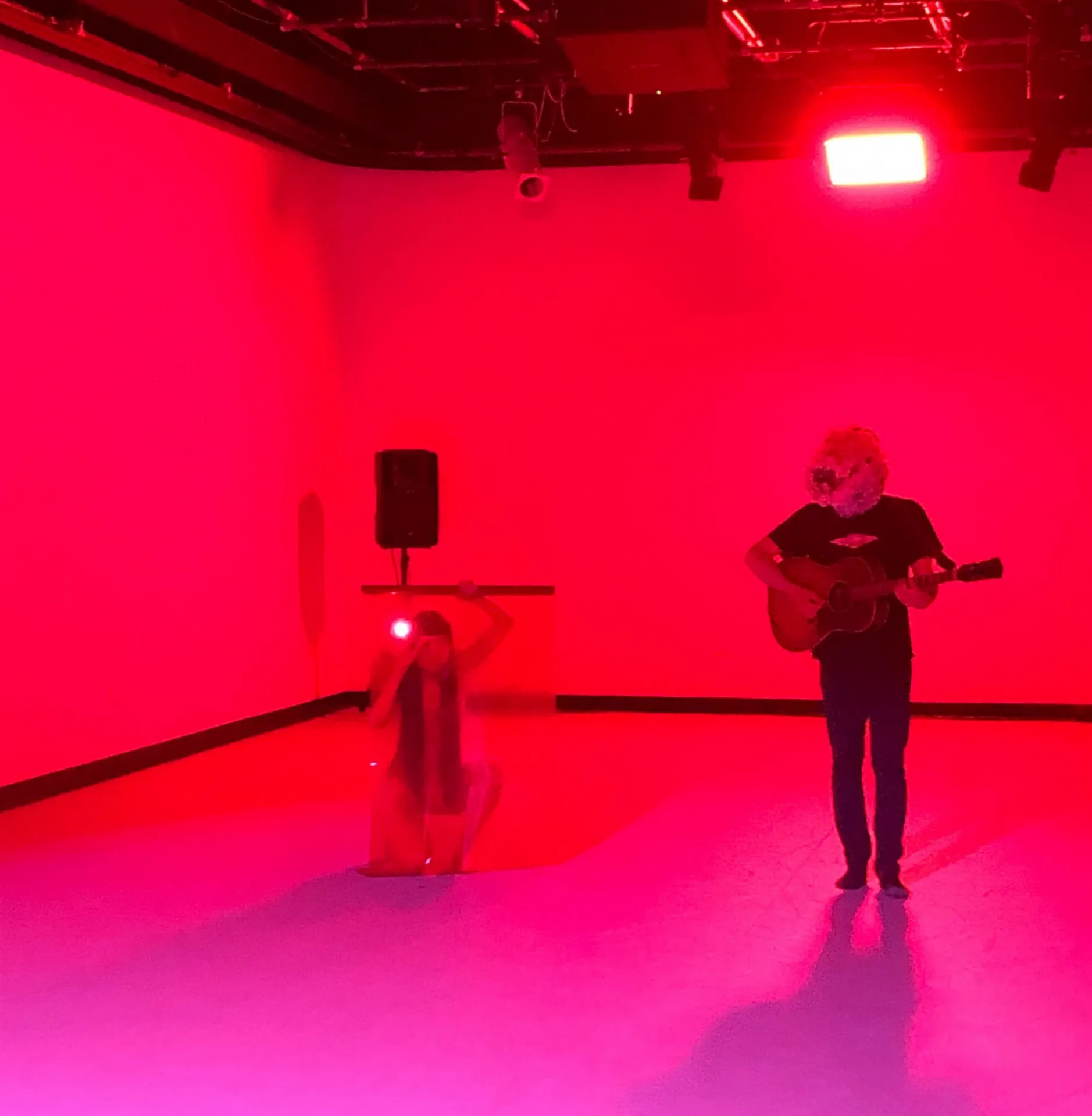 A person playing guitar in a very red-lit room.