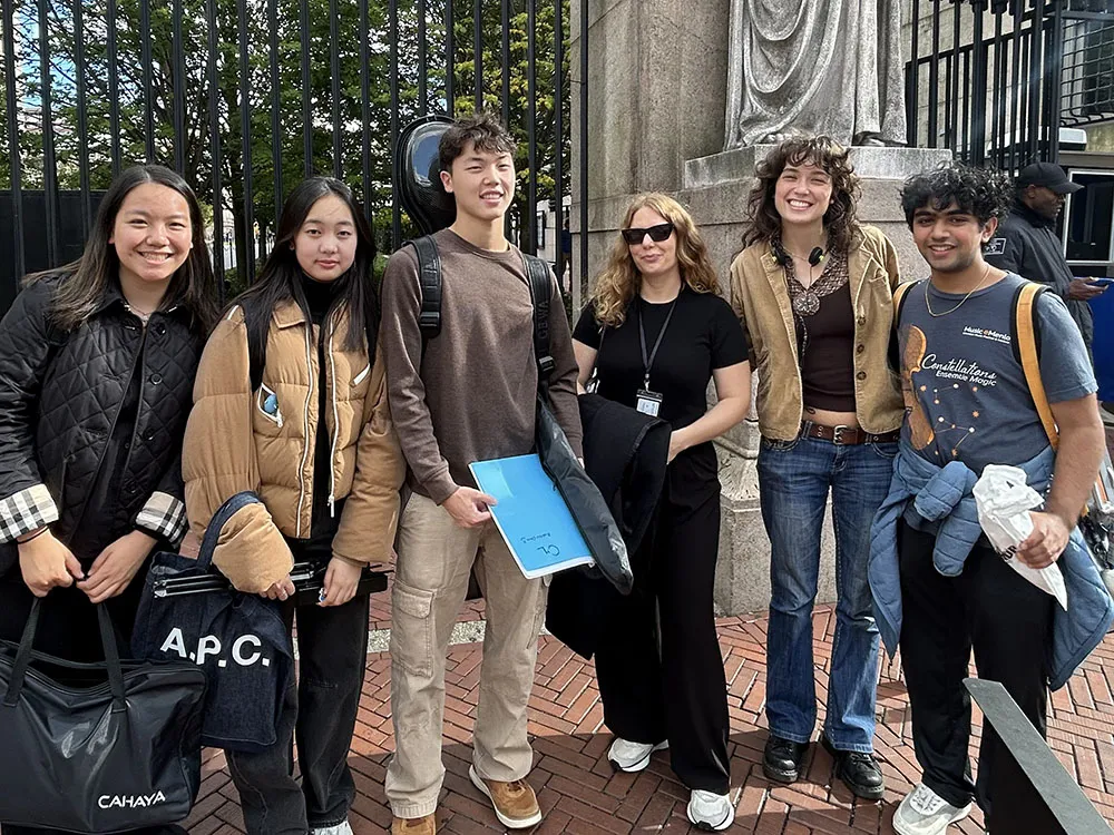 Liyu Chen (violin), Yuli Choi (violin), Andrew Chun (cello), Audrey Amsellem, Avery Pratho, and Tejas Tirthapura (viola). They are in front of Columbia's gates and smiling.
