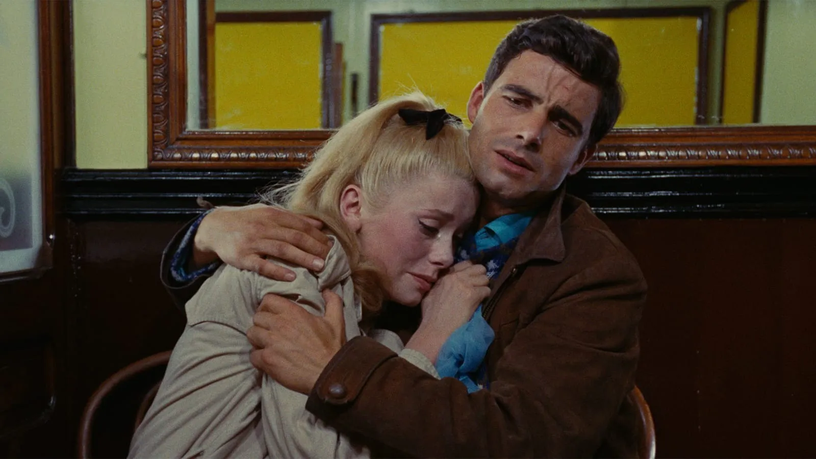 Screencap from The Umbrellas of Cherbourg (Les Parapluies de Cherbourg). A man holds a crying woman in his arms.