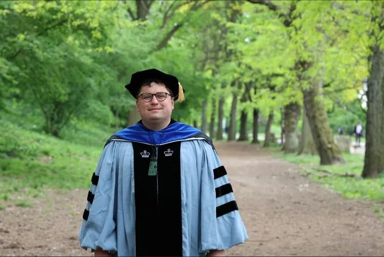 Photo of Callum outside in Columbia's academic regalia.