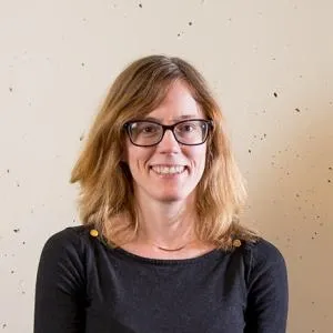 Marianna Ritchey in a black top in front of a white wall. She's smiling at the camera.