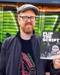 Dr. Rollefson holding a copy of "Flip The Script."